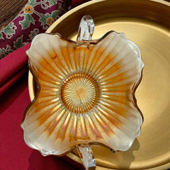 Vintage Fenton marigold carnival glass dish with stippled rays pattern, featuring a ruffled scalloped edge and clear double handles; warm amber iridescence with visible air bubbles 