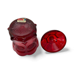 Vintage Fostoria Ruby Red Coin Glass candy dish with lid, featuring embossed coin medallions and a pointed finial; shown in rich red pressed glass with original Fostoria sticker, styled to highlight its collectible elegance and mid-century provenance.