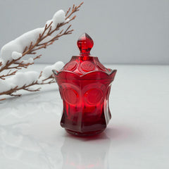 Vintage Fostoria Ruby Red Coin Glass candy dish with lid, featuring embossed coin medallions and a pointed finial; shown in rich red pressed glass with original Fostoria sticker, styled to highlight its collectible elegance and mid-century provenance.