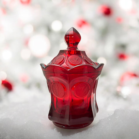 Vintage Fostoria Ruby Red Coin Glass candy dish with lid, featuring embossed coin medallions and a pointed finial; shown in rich red pressed glass with original Fostoria sticker, styled to highlight its collectible elegance and mid-century provenance.