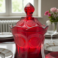 Vintage Fostoria Ruby Red Coin Glass candy dish with lid, featuring embossed coin medallions and a pointed finial; shown in rich red pressed glass with original Fostoria sticker, styled to highlight its collectible elegance and mid-century provenance.