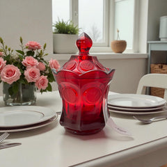 Vintage Fostoria Ruby Red Coin Glass candy dish with lid, featuring embossed coin medallions and a pointed finial; shown in rich red pressed glass with original Fostoria sticker, styled to highlight its collectible elegance and mid-century provenance.