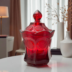 Vintage Fostoria Ruby Red Coin Glass candy dish with lid, featuring embossed coin medallions and a pointed finial; shown in rich red pressed glass with original Fostoria sticker, styled to highlight its collectible elegance and mid-century provenance.