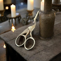 Antique French stork-shaped embroidery scissors from the late 1800s to early 1900s. Crafted with intricate details, the silver-tone finish shows charming wear, revealing darker metal and hints of faded gold-tone accents on the stork’s body when opened. A collectible and decorative piece embodying timeless craftsmanship and vintage elegance.