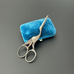 Antique French stork-shaped embroidery scissors from the late 1800s to early 1900s. Crafted with intricate details, the silver-tone finish shows charming wear, revealing darker metal and hints of faded gold-tone accents on the stork’s body when opened. A collectible and decorative piece embodying timeless craftsmanship and vintage elegance.