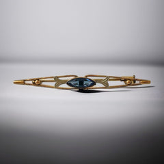 Vintage French Art Deco bar brooch with blue marquise rhinestone, gold-plated metal, and silver-tone leaf accents