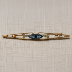 Vintage French Art Deco bar brooch with blue marquise rhinestone, gold-plated metal, and silver-tone leaf accents