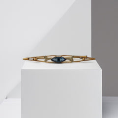 Vintage French Art Deco bar brooch with blue marquise rhinestone, gold-plated metal, and silver-tone leaf accents