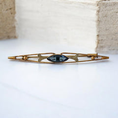 Vintage French Art Deco bar brooch with blue marquise rhinestone, gold-plated metal, and silver-tone leaf accents