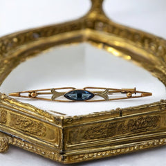 Vintage French Art Deco bar brooch with blue marquise rhinestone, gold-plated metal, and silver-tone leaf accents