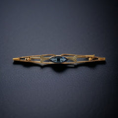 Vintage French Art Deco bar brooch with blue marquise rhinestone, gold-plated metal, and silver-tone leaf accents