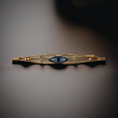 Vintage French Art Deco bar brooch with blue marquise rhinestone, gold-plated metal, and silver-tone leaf accents