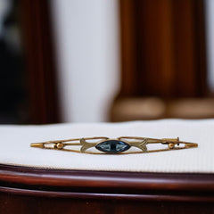 Vintage French Art Deco bar brooch with blue marquise rhinestone, gold-plated metal, and silver-tone leaf accents