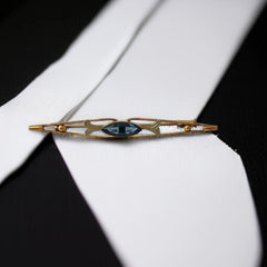 Vintage French Art Deco bar brooch with blue marquise rhinestone, gold-plated metal, and silver-tone leaf accents