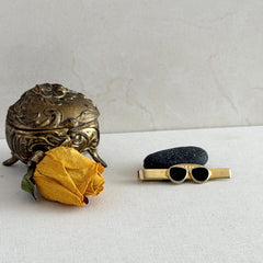 Vintage French gold‑tone tie clip with black enamel sunglasses motif from the 1980s.