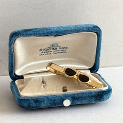 Vintage French gold‑tone tie clip with black enamel sunglasses motif from the 1980s.