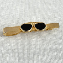 Vintage French gold‑tone tie clip with black enamel sunglasses motif from the 1980s.