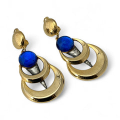 Vintage French modernist clip-on earrings with faceted blue round cabochons, layered gold and silver-tone metal crescents, and long sculptural dangles; shown from multiple angles to highlight texture, asymmetry, and mixed-metal design.