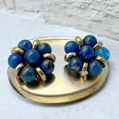 Vintage French clip-on earrings featuring marbled blue plastic beads with gold veining, arranged in a floral cluster with gold-tone rondelles, 1970s–1980s design, shown in very good condition.