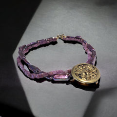 Necklace with vintage 1930s French gold‑tone floral brooch pendant on two strands of purple‑pink dyed stick pearls and rough rubies, shown from multiple angles.