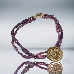 Necklace with vintage 1930s French gold‑tone floral brooch pendant on two strands of purple‑pink dyed stick pearls and rough rubies, shown from multiple angles.