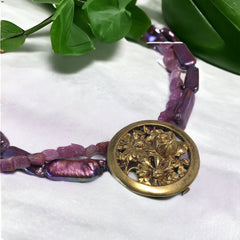 Necklace with vintage 1930s French gold‑tone floral brooch pendant on two strands of purple‑pink dyed stick pearls and rough rubies, shown from multiple angles.
