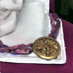 Necklace with vintage 1930s French gold‑tone floral brooch pendant on two strands of purple‑pink dyed stick pearls and rough rubies, shown from multiple angles.