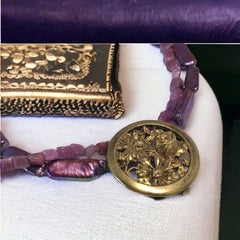Necklace with vintage 1930s French gold‑tone floral brooch pendant on two strands of purple‑pink dyed stick pearls and rough rubies, shown from multiple angles.