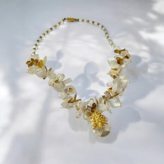 Vintage French necklace from the 1980s featuring iridescent acrylic beads, frosted and clear leaf accents, gold-tone metal details, and a central faceted pear-shaped drop with floral embellishment. Nature-inspired design in very good vintage condition