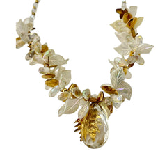 Vintage French necklace from the 1980s featuring iridescent acrylic beads, frosted and clear leaf accents, gold-tone metal details, and a central faceted pear-shaped drop with floral embellishment. Nature-inspired design in very good vintage condition