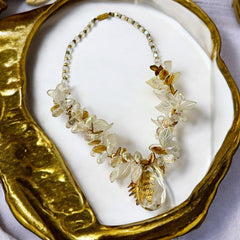 Vintage French necklace from the 1980s featuring iridescent acrylic beads, frosted and clear leaf accents, gold-tone metal details, and a central faceted pear-shaped drop with floral embellishment. Nature-inspired design in very good vintage condition