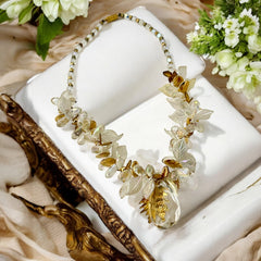 Vintage French necklace from the 1980s featuring iridescent acrylic beads, frosted and clear leaf accents, gold-tone metal details, and a central faceted pear-shaped drop with floral embellishment. Nature-inspired design in very good vintage condition