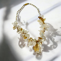 Vintage French necklace from the 1980s featuring iridescent acrylic beads, frosted and clear leaf accents, gold-tone metal details, and a central faceted pear-shaped drop with floral embellishment. Nature-inspired design in very good vintage condition