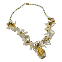 Vintage French necklace from the 1980s featuring iridescent acrylic beads, frosted and clear leaf accents, gold-tone metal details, and a central faceted pear-shaped drop with floral embellishment. Nature-inspired design in very good vintage condition