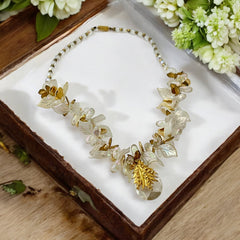 Vintage French necklace from the 1980s featuring iridescent acrylic beads, frosted and clear leaf accents, gold-tone metal details, and a central faceted pear-shaped drop with floral embellishment. Nature-inspired design in very good vintage condition