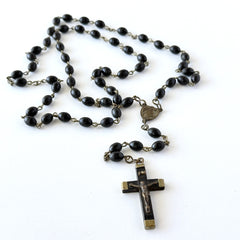 Vintage French ebony and silver‑tone rosary with black boxwood beads and signed cross, photographed on light fabric background.