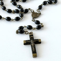 Vintage French ebony and silver‑tone rosary with black boxwood beads and signed cross, photographed on light fabric background.