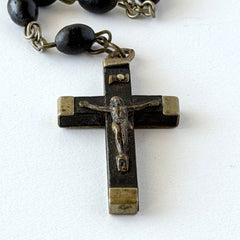 Vintage French ebony and silver‑tone rosary with black boxwood beads and signed cross, photographed on light fabric background.