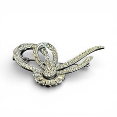 Vintage French bow brooch with clear rhinestones in rhodium-plated metal, featuring pavé chatons and baguettes in a sculptural 1950s design.