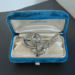 Vintage French bow brooch with clear rhinestones in rhodium-plated metal, featuring pavé chatons and baguettes in a sculptural 1950s design.