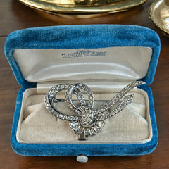 Vintage French bow brooch with clear rhinestones in rhodium-plated metal, featuring pavé chatons and baguettes in a sculptural 1950s design.