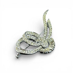 Vintage French bow brooch with clear rhinestones in rhodium-plated metal, featuring pavé chatons and baguettes in a sculptural 1950s design.