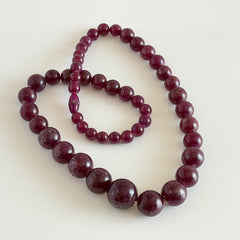 Vintage French plum‑colored graduated bead necklace with a matching screw clasp, shown on display props from multiple angles.