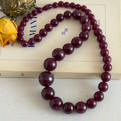 Vintage French plum‑colored graduated bead necklace with a matching screw clasp, shown on display props from multiple angles.
