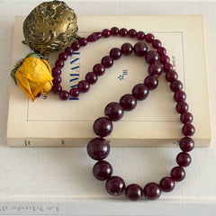 Vintage French plum‑colored graduated bead necklace with a matching screw clasp, shown on display props from multiple angles.