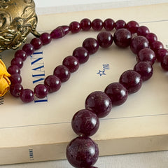 Vintage French plum‑colored graduated bead necklace with a matching screw clasp, shown on display props from multiple angles.