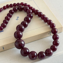 Vintage French plum‑colored graduated bead necklace with a matching screw clasp, shown on display props from multiple angles.