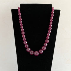 Vintage French plum‑colored graduated bead necklace with a matching screw clasp, shown on display props from multiple angles.