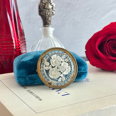 Vintage 1930s French round brooch with reverse carved Lucite floral center and gold tone metal frame, shown from various angles.