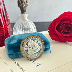 Vintage 1930s French round brooch with reverse carved Lucite floral center and gold tone metal frame, shown from various angles.